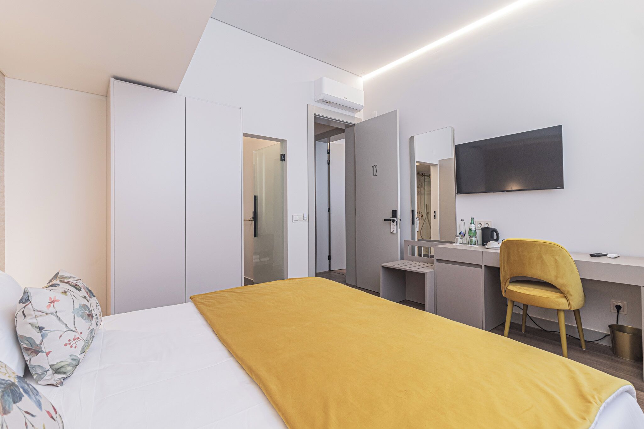 Una moderna camera d'albergo con un letto, una scrivania, una sedia e una televisione.