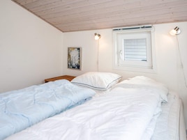 Quarto com duas camas, janela com persianas, luminária fixada na parede e um quadro.