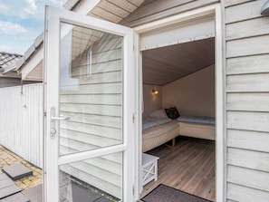 Eine kleine, einführende Blockhütte mit einer Schiebetür, einem Bett, einem Nachttisch, einer Wandlampe und einem kleinen Tisch.