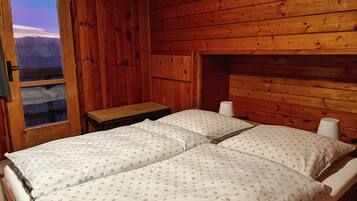 Una habitación de cabaña de madera con una cama, una mesita de noche y una ventana.