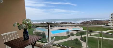 A balcony with a view of the ocean and a pool.