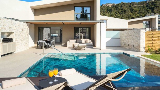 Une maison moderne dotée d’une piscine, d’un espace extérieur aménagé et d’un coin cuisine.