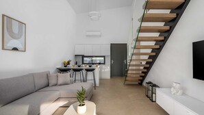 Un espace de vie moderne comprenant un canapé, une table basse, un coin cuisine et un escalier.