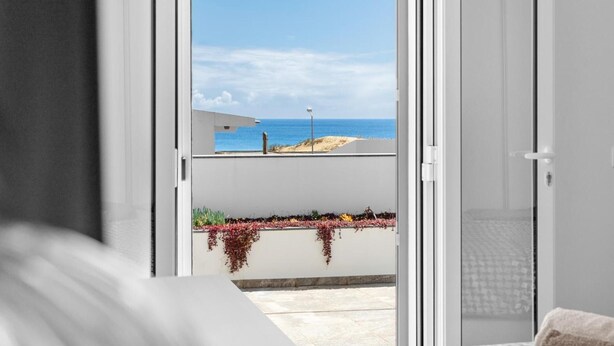 A room with a view of the sea through an open door, a bed, and a small balcony with plants. - Holiday Home 'Casa Do Cabeco' with Sea View and Wi-Fi (Cabeco de Ponta)