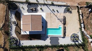 Vista aérea de una propiedad con piscina, terraza cubierta y zonas ajardinadas.