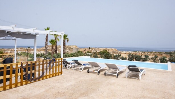 A poolside area with lounge chairs, a hammock, and a view of the sea and landscape. - Casa Pietra Bianca | Cornino Bay | Modern comfort | Private pool | Sicily (Castellammare del Golfo)