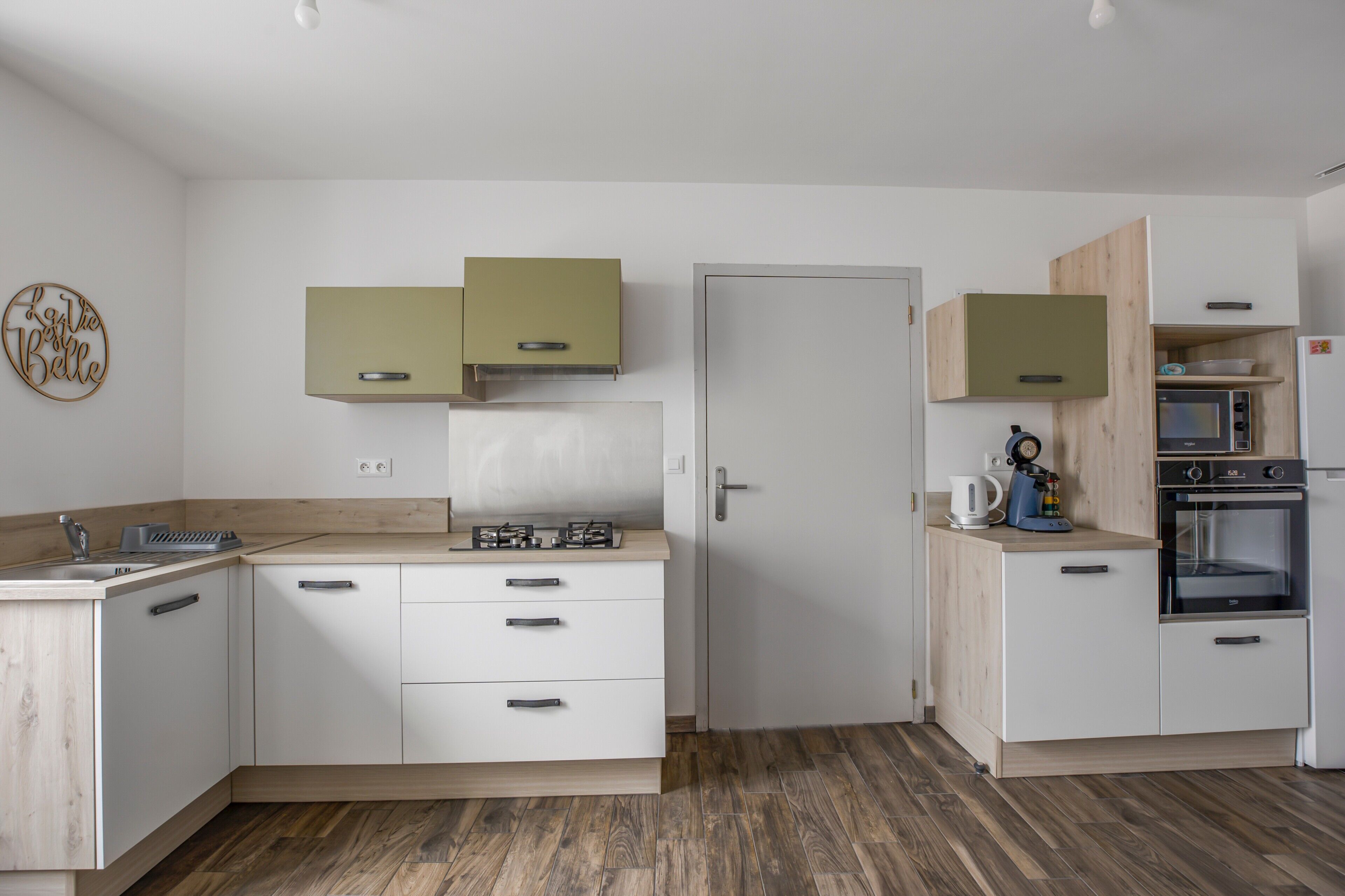 Een moderne keuken met witte kasten, een houten aanrechtblad en ingebouwde apparatuur.