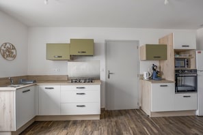 Une cuisine moderne avec des meubles blancs, un plan de travail en bois et des appareils électroménagers intégrés.