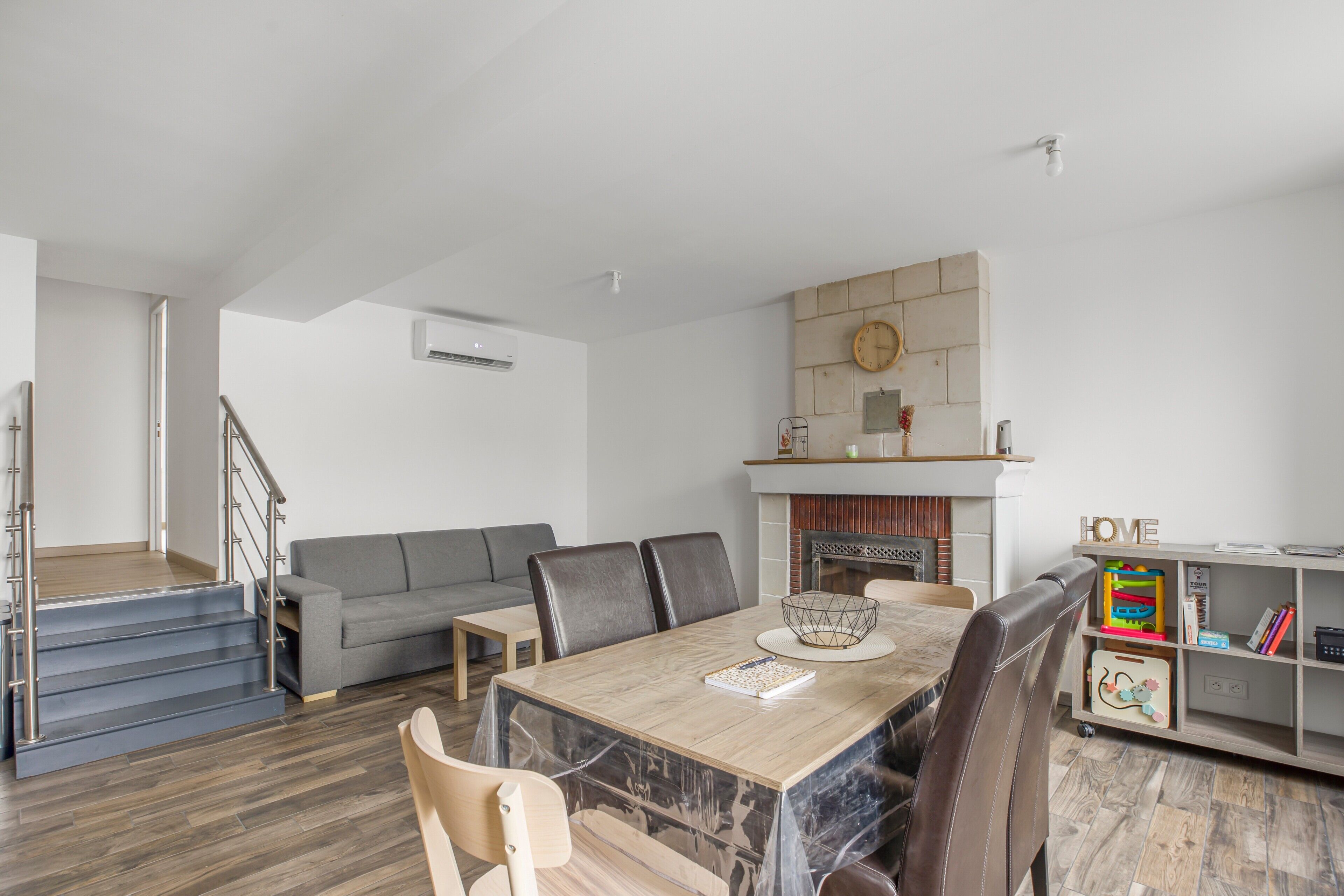 Ein modernes Wohnzimmer mit Essbereich, Treppe und Kamin.