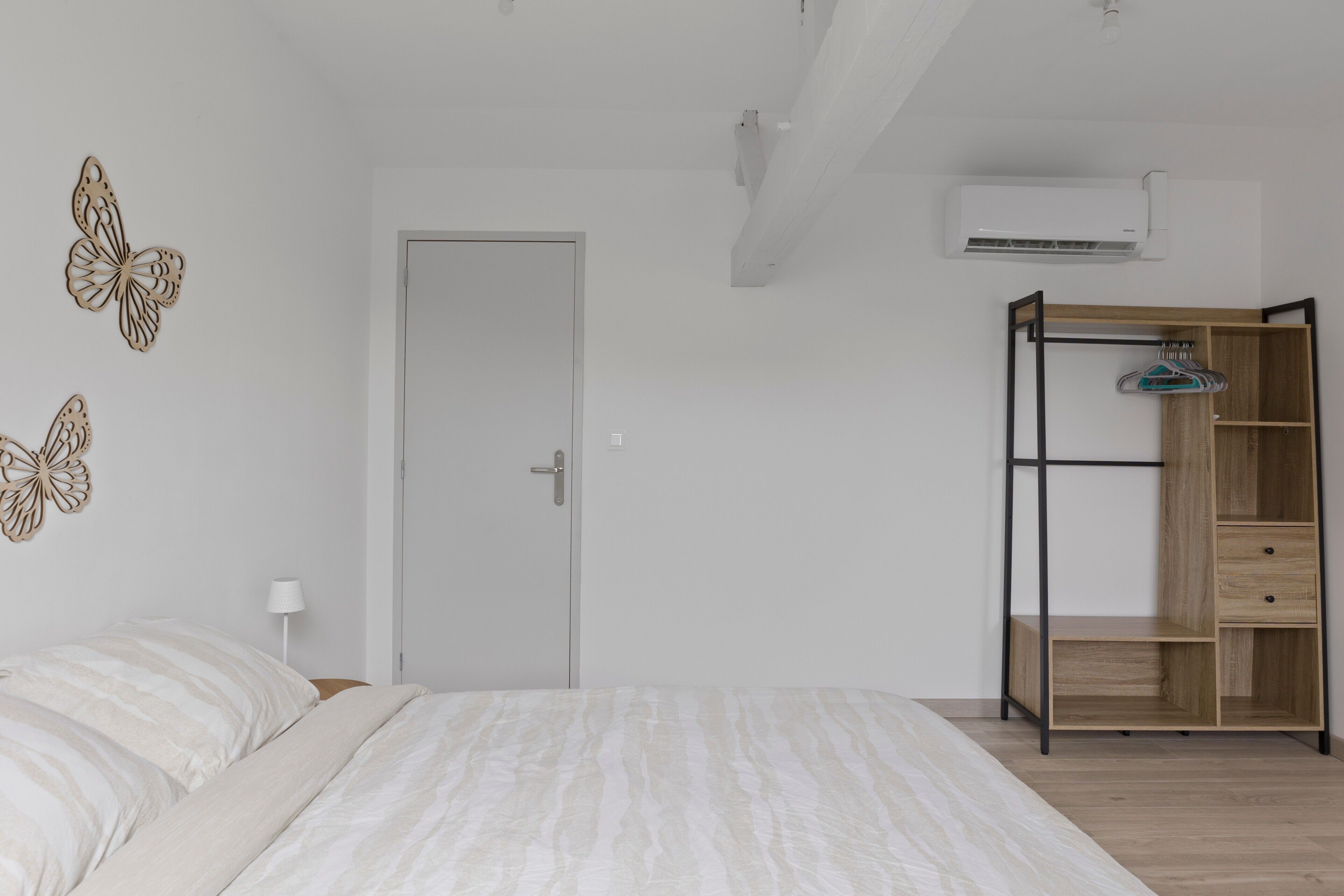 Une chambre à coucher avec un lit, une armoire, une porte et des papillons décoratifs fixés au mur.