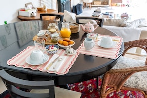 A round dining table with placemats, a teapot, cups, a jug, and a bowl of food.