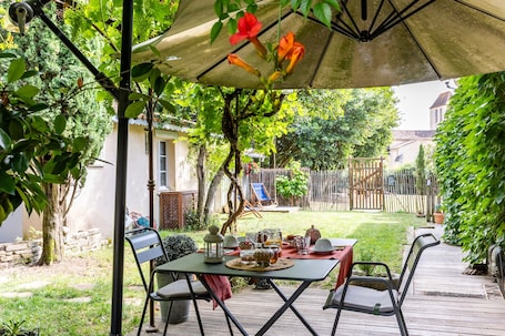 A patio with a table set for a meal, surrounded by chairs, under a canopy.. Le Clos du Gorion – Guest Room in the Countryside