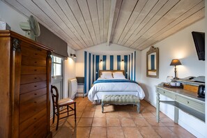 A bedroom with a bed, a wooden dresser, a chair, a bench, a desk, and a mirror. - Le Clos du Gorion – Guest Room in the Countryside (Saint-Sulpice et Cameyrac)