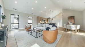 En rummelig opholdsstue med sofa, sofabord og spisebord med stole.