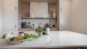 A modern kitchen with a marble countertop, wooden cabinets, and various kitchen appliances.