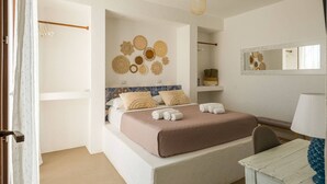 A bedroom with a bed, a bedside table, a chair, a mirror, and wall decor. - Casa Maruzza | Scopello | Sea-view retreat with infinity pool (Castellammare del Golfo)