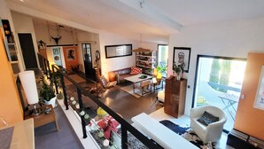 En rummelig opholdsstue med højt til loftet, en trappe og en balkon med udsigt.