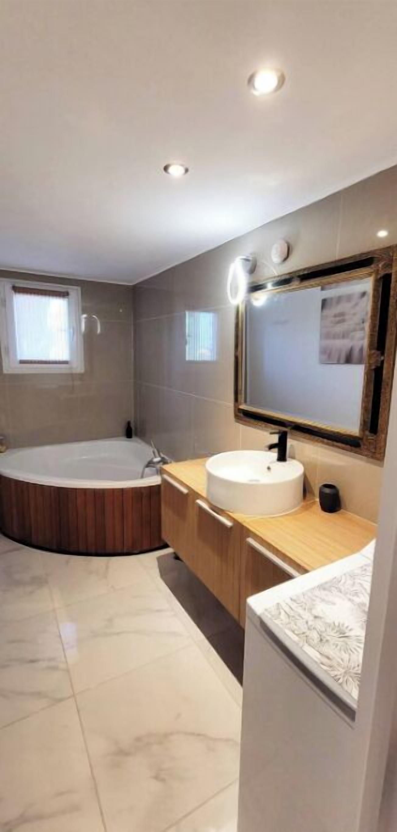 Une salle de bain moderne avec une baignoire sur pieds, un lavabo rond et un grand miroir.