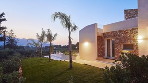Een modern huis met een stenen gevel, een verzorgd gazon en een uitzicht op de bergen op de achtergrond.