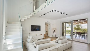 Een moderne woonkamer met een trap, een flatscreen televisie, een bank en een eethoek met uitzicht.