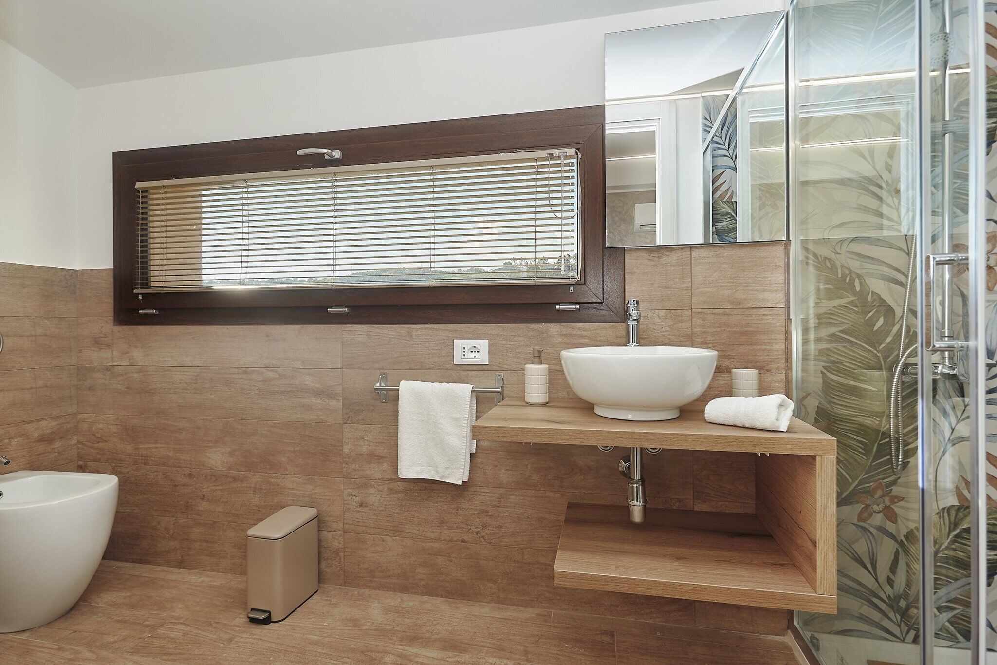 A modern bathroom with a large sink, a toilet, and a shower.