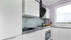 Una cocina moderna con armarios blancos, un lavabo negro y una ventana con vistas a la ciudad.