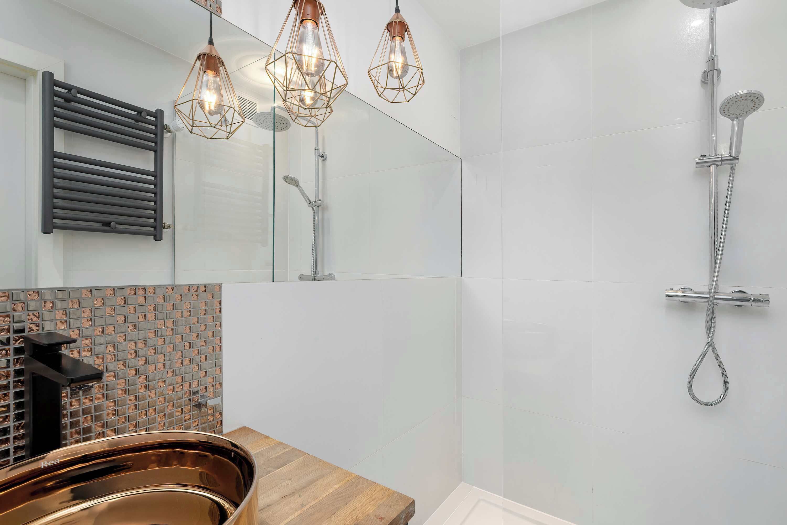 Een moderne badkamer met een douchecabine van glas, een houten wastafelmeubel en een spiegel met een handdoekhouder.