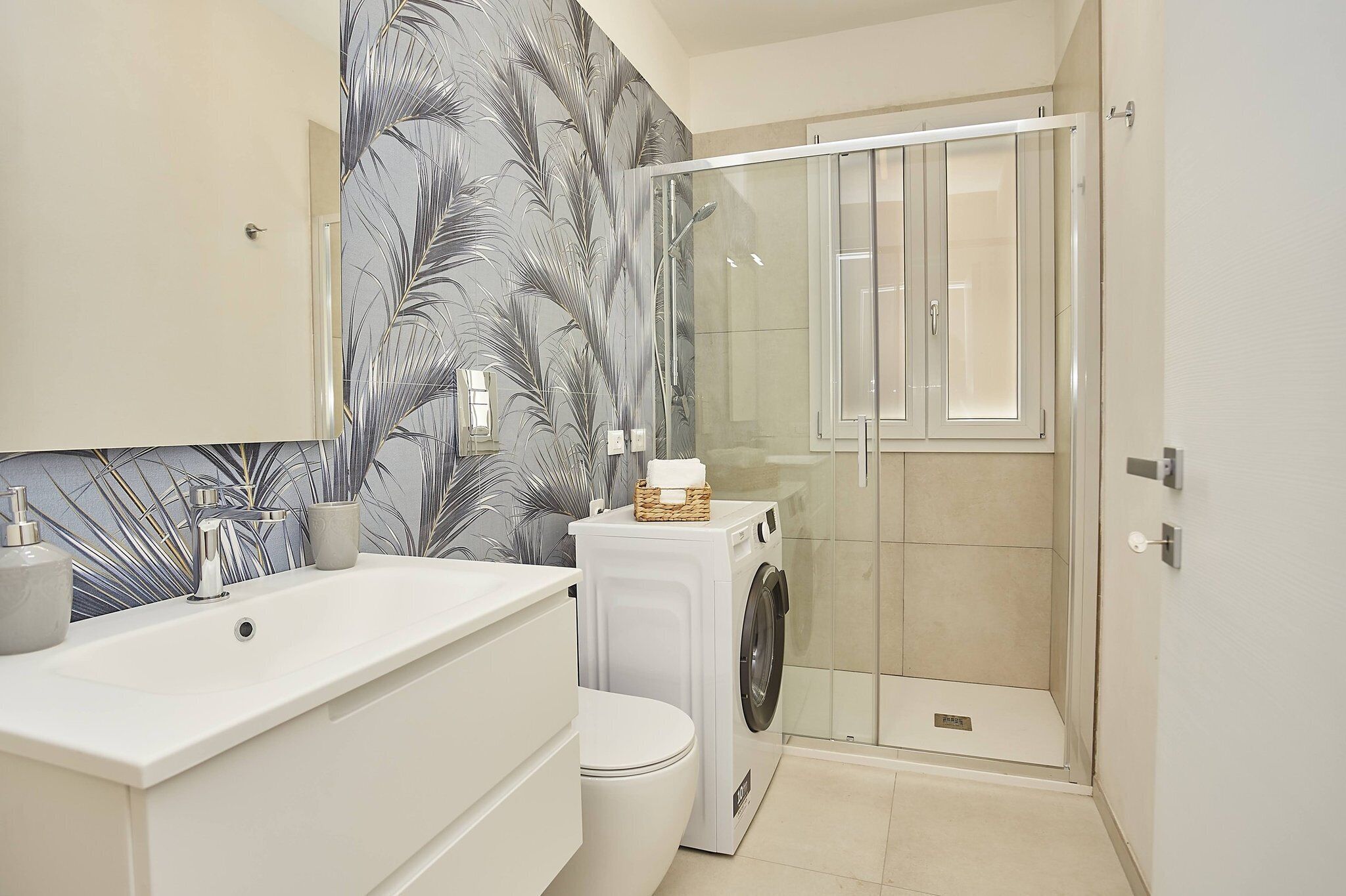 Une salle de bain moderne avec un lavabo, des toilettes et un lave-linge, le tout de couleur blanche.