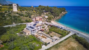 Vista aérea de una propiedad costera con un edificio grande, un faro y una playa.