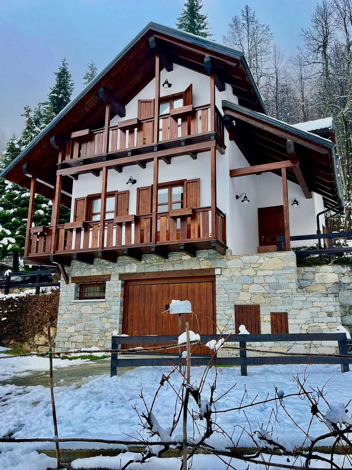 A chalet-style building with a stone foundation, wooden balconies, and a large wooden door.