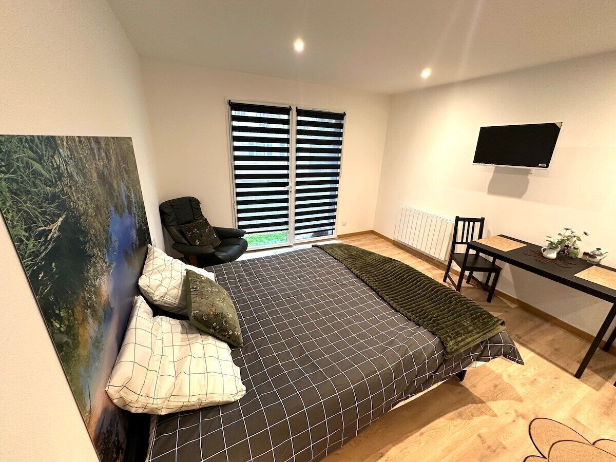 Un dormitorio moderno con cama, escritorio, silla y un cuadro grande en la pared.