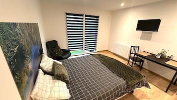 Un dormitorio moderno con cama, escritorio, silla y un cuadro grande en la pared.