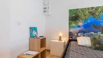 A bedroom with a bed, a nightstand, a wooden shelf, and a wall-mounted air conditioner.
