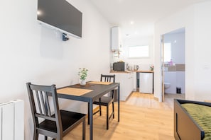 A compact living space with a dining area, kitchenette, and a small bathroom.