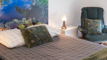 Une chambre à coucher avec un lit, une chaise, une lampe et un grand tableau mural.