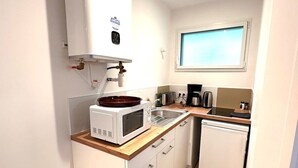 A compact kitchen with a built-in microwave, a coffee maker, a sink, and a dishwasher. - New Studio Rivage Garden Floor (Plouédern)