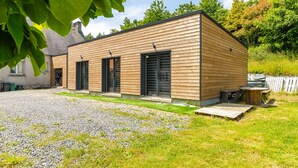 A modern wooden building with a gravel driveway and a grassy lawn. - New Studio Rivage Garden Floor (Plouédern)