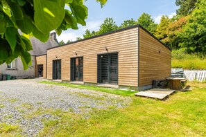 A modern wooden building with a gravel driveway and a grassy lawn. - New Studio Rivage Garden Floor (Plouédern)
