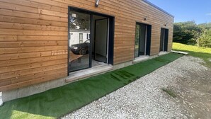 Un bâtiment moderne avec un revêtement mural en bois, de grandes portes vitrées et une allée gravillonnée.