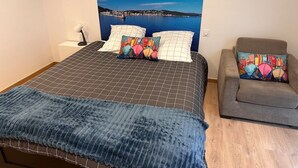 Une chambre à coucher avec un lit, un canapé et une grande fenêtre donnant sur un plan d’eau.