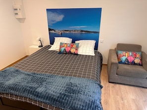 Une chambre à coucher avec un lit, un canapé et une grande fenêtre donnant sur un plan d’eau.