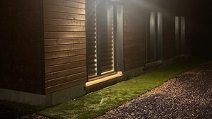 A modern building with a wooden exterior and a lit entrance. - Ancrage New Studio Garden Floor (Plouedern)