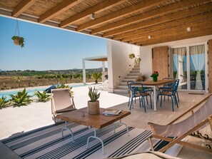Eine moderne Terrassenanlage im Freien mit Pool, Holzmöbeln und Blick ins Grüne.