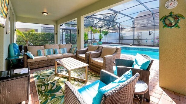 Un espace extérieur aménagé avec des meubles en osier, abrité par une structure, comprenant une piscine et une serre.