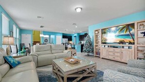 Un salon doté d’un grand téléviseur à écran plat, d’un sapin de Noël et d’un coin salon confortable.