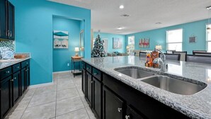 Une cuisine aux murs de couleur turquoise, dotée de plans de travail en granit et d’un évier à deux bacs.