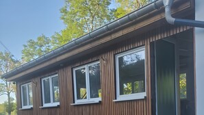 A wooden building with a ramp leading to a door, a window, and a bench outside. - Apartment "Unit 1" with Mountain View, Private Garden, and Wi-Fi (Bärenstein)