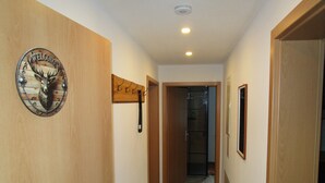 A hallway with wooden walls, a welcome sign, a coat rack, and a door leading to another room. - Apartment "Unit 1" with Mountain View, Private Garden, and Wi-Fi (Bärenstein)