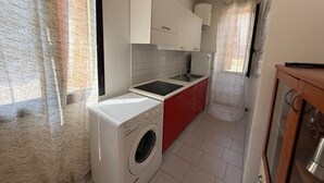 Eine kleine Küche mit Waschmaschine, Spüle und Herd.