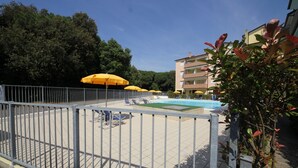 Area piscina con ombrelloni gialli, poltrone a sdraio e piscina recintata.